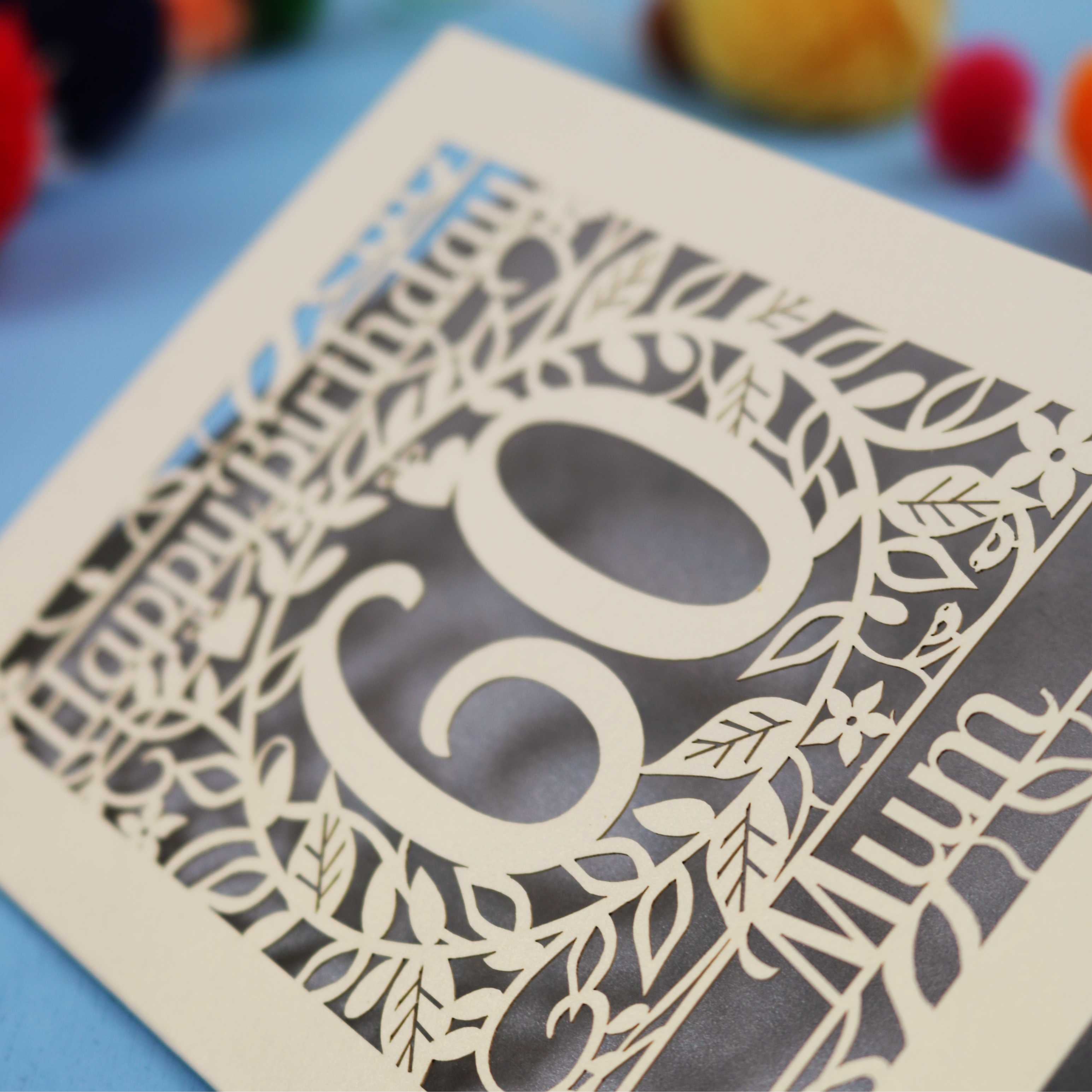 Decorative laser cut birthday card with cut-out numbers '60' and floral patterns on a blue background