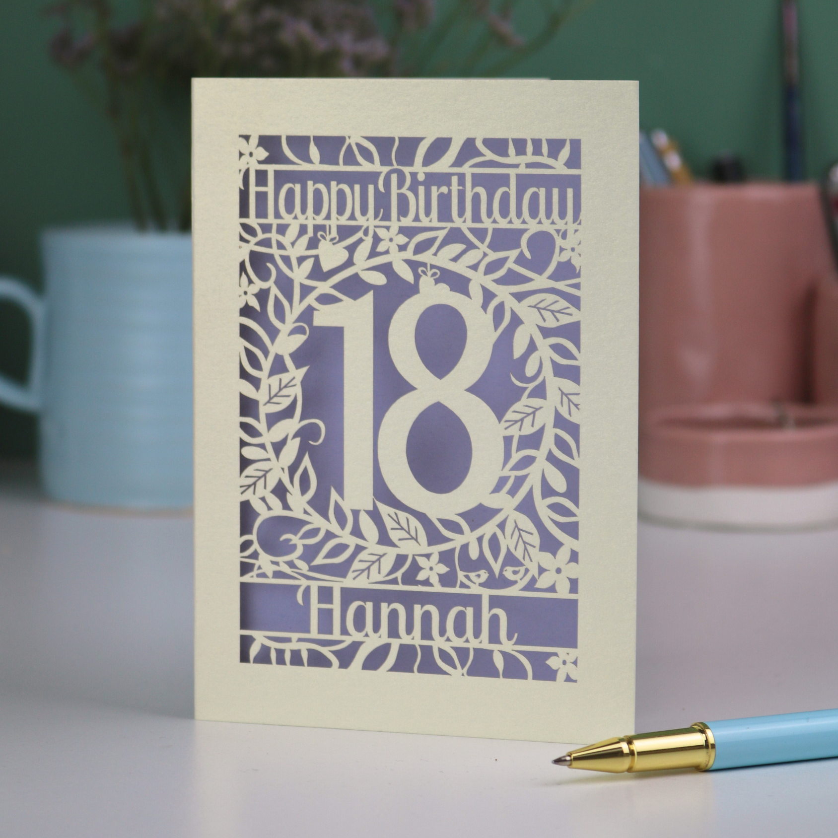 Personalized 18th birthday card with number 18 on a table with a pen and plants in the background