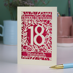 Personalised 18th Birthday card with 'Happy Birthday 18 Hannah' on a desk with a pen and mug.