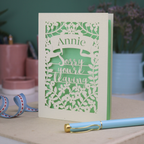 Laser cut leaving Card with 'Sorry you're leaving' message on a desk with decorative items.