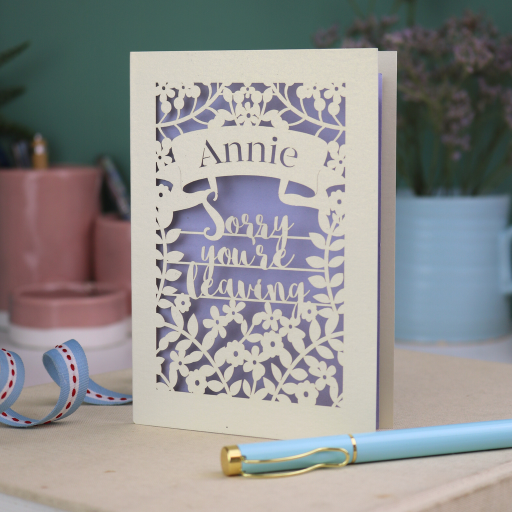 Laser cut leaving Card with 'Sorry you're leaving' message on a desk with decorative items.