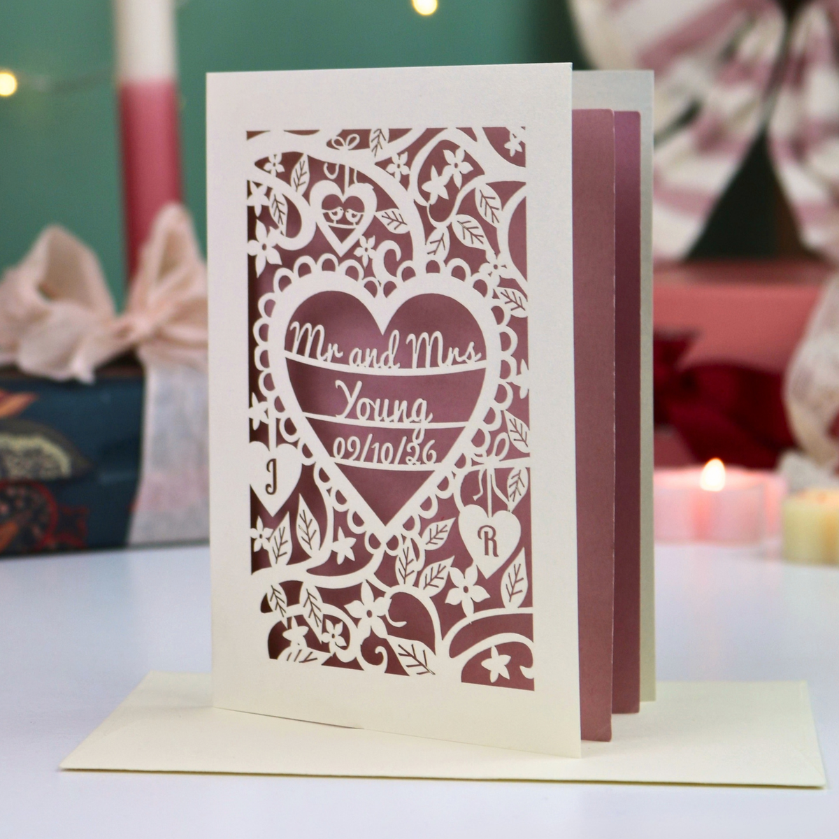 A laser-cut wedding card with an intricate heart-shaped design and the text 'Mr. and Mrs. Young, 09/10/26'