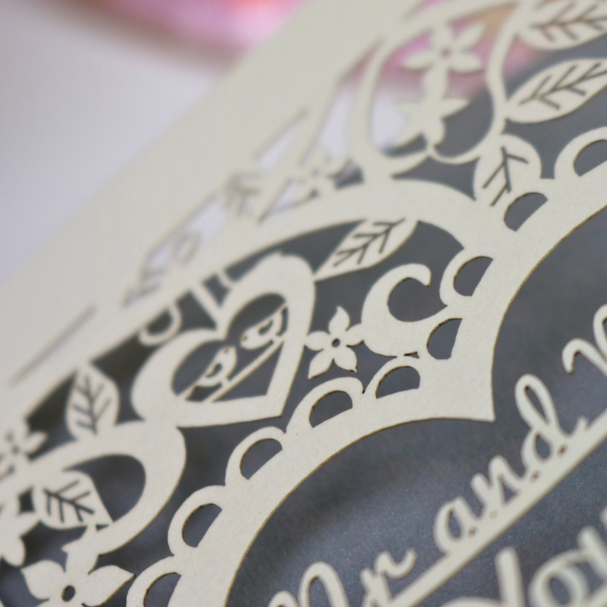 Close up of laser cut wedding card with tiny birds sitting in a heart shape