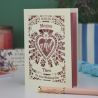 Personalised Wedding card with names and date, featuring a heart design, on a surface with stationery items.