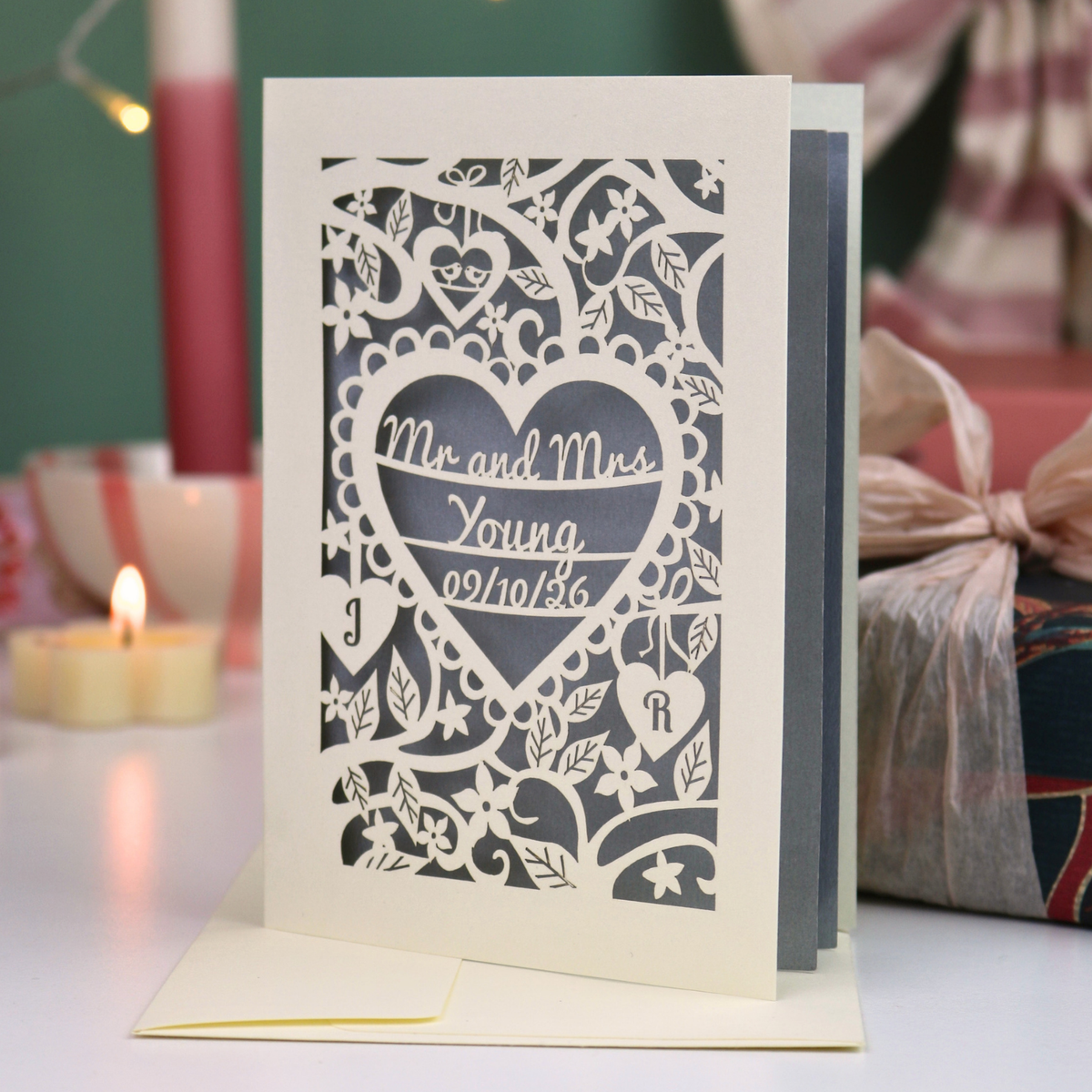 A laser-cut wedding card with an intricate heart-shaped design and the text 'Mr. and Mrs. Young, 09/10/26'