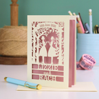 Personalized laser-cut lesbian anniversary card with cut-out silhouettes of a couple, text, and a pen on a desk.