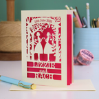 Personalised card with cut-out design of two women holding hands, text '16th June 2026', 'Lizzie and Rach', on a pink background.