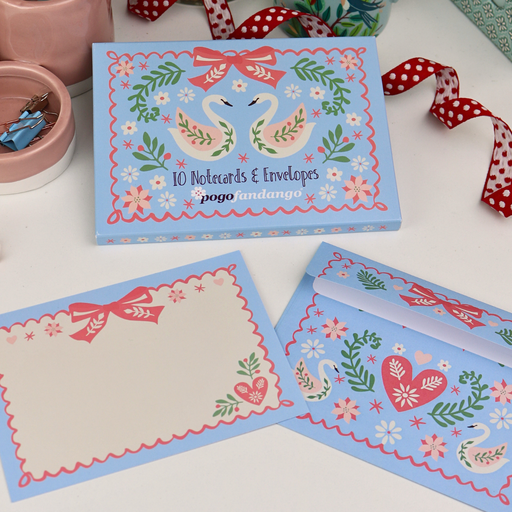 Set of notecards with envelopes featuring swan designs on a white surface.