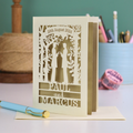 Personalized card with laser-cut design of two male figures holding hands, with text '20th August 2024', 'PAUL', and 'MARCUS' on a desk.