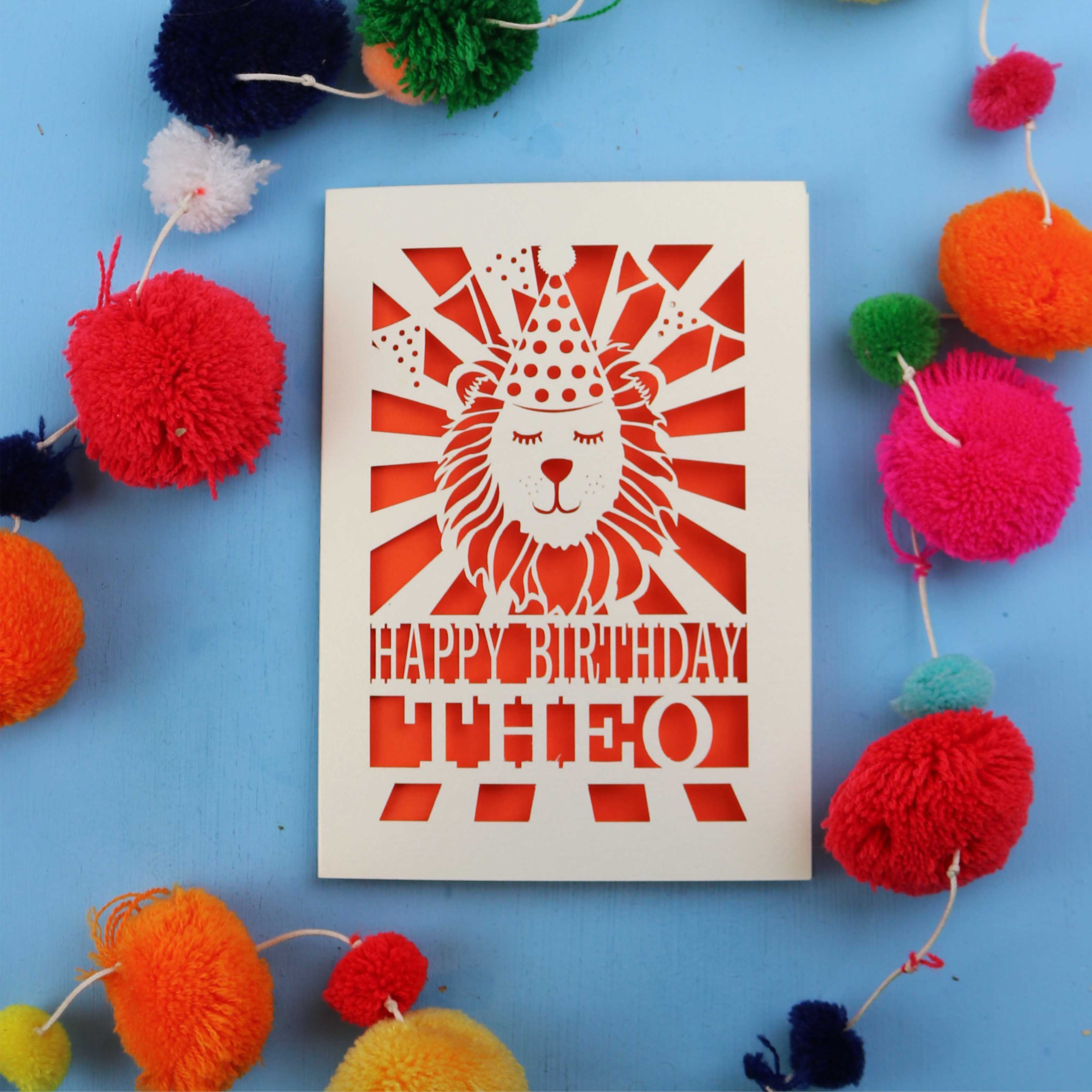 Birthday card with lion design and colourful pom-poms on a blue background
