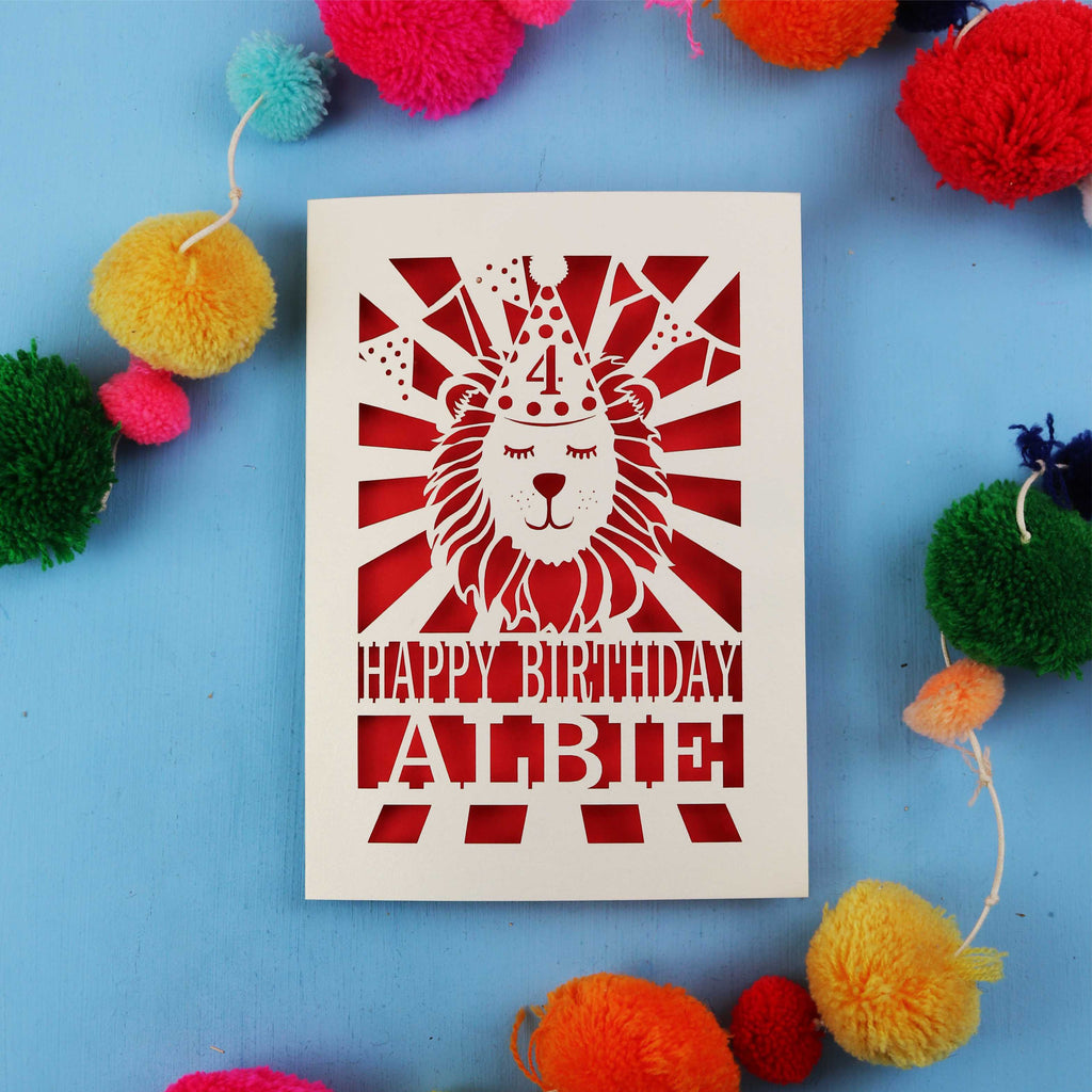 Laser Cut Birthday card with lion design and colourful pom-poms on a blue background