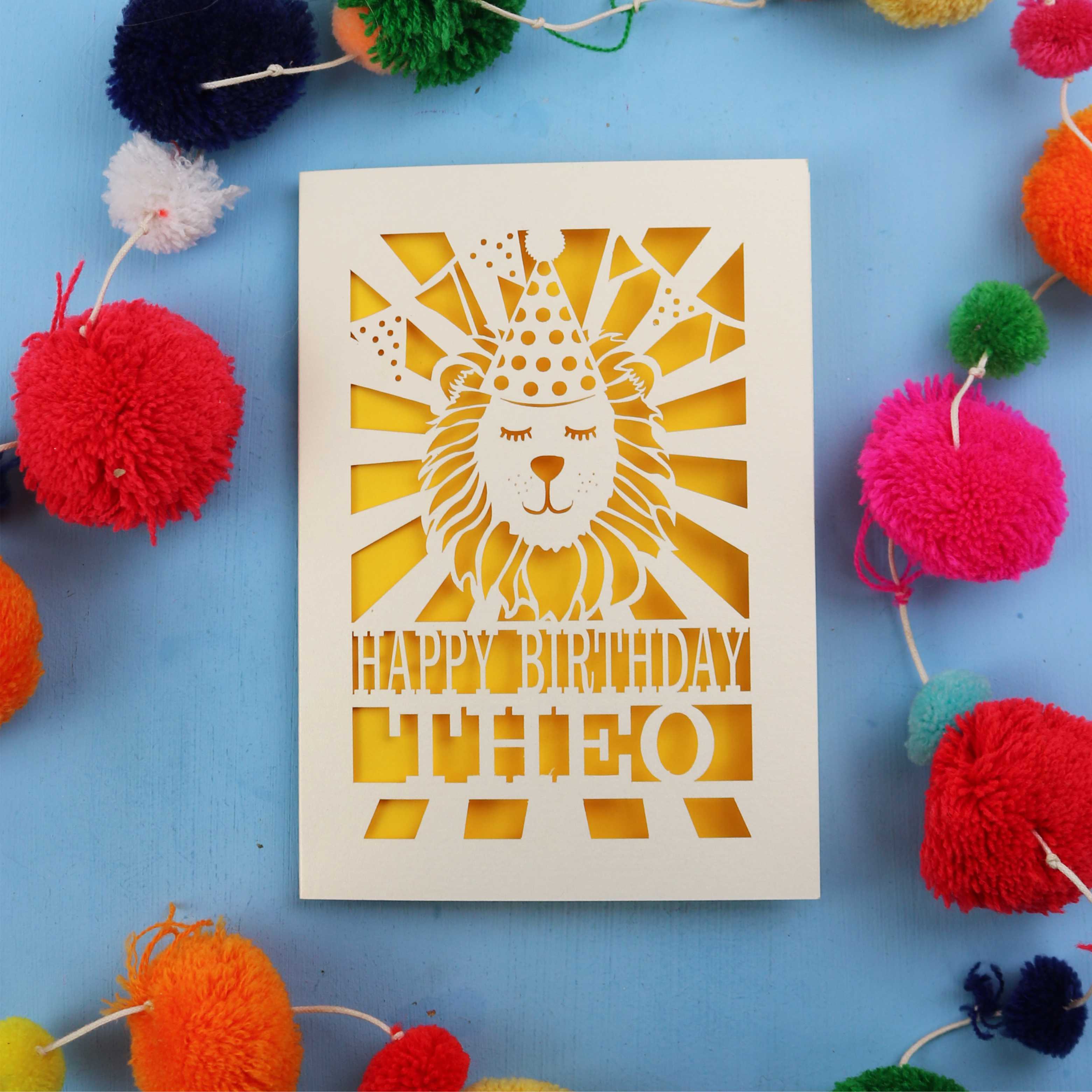 Birthday card with lion design and colourful pom-poms on a blue background