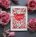 Laser cut engagement card with 'love' inside a floral heart design 