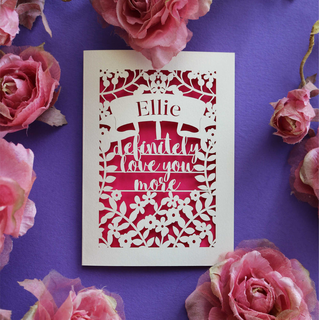 A personalised cut out Valentine's card that says "I definitely love you more"