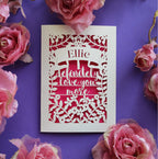 A personalised cut out Valentine's card that says "I definitely love you more"