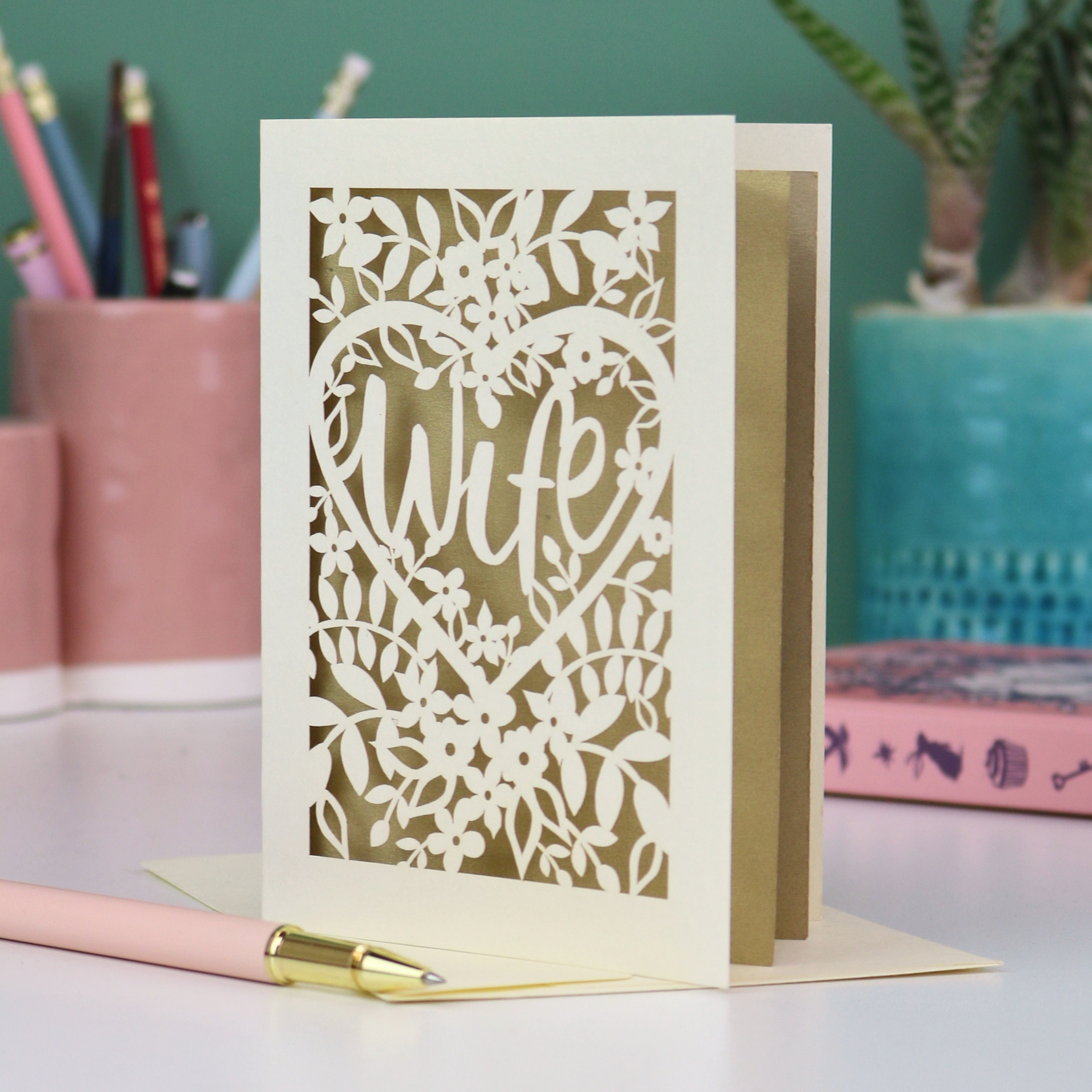 Luxury Greeting card with 'Wife' and floral heart design on a desk with stationery items.