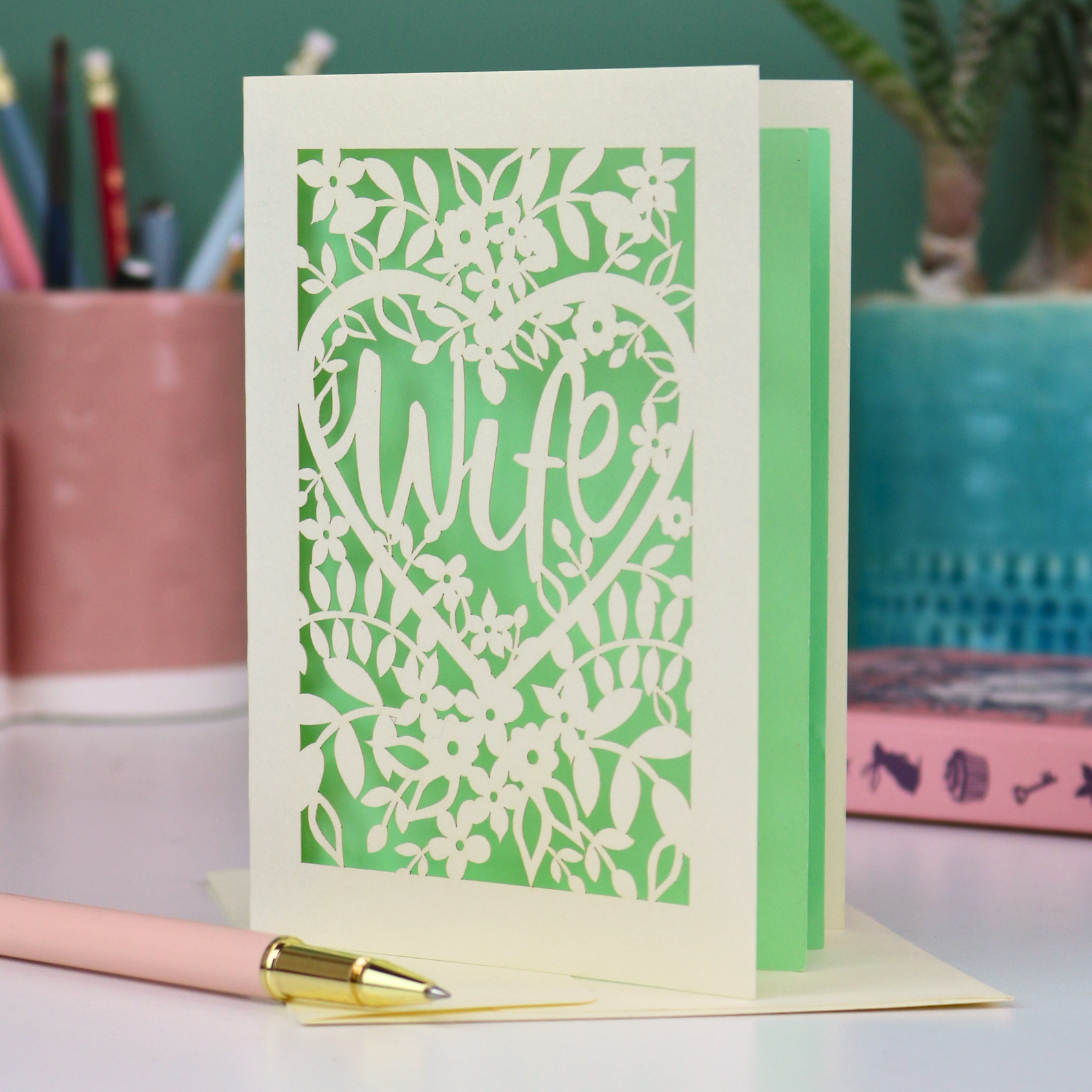 Luxury Wife Greeting card with floral heart design on a desk with stationery items.