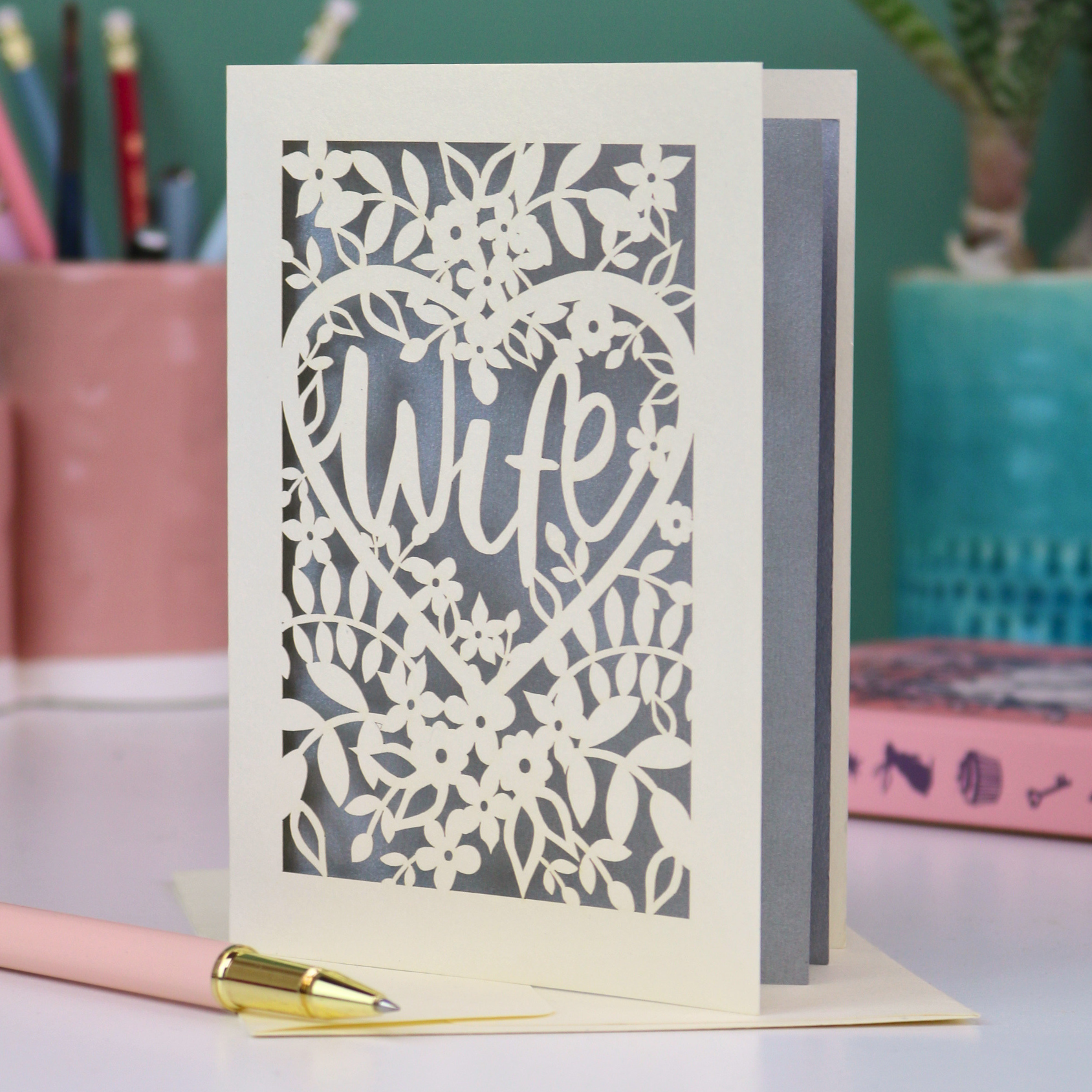 Luxury Card with 'Wife' cut out design on a desk with stationery items.