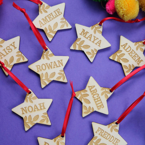Personalised Christmas decorations in the shape of stars with names engraved on wood. - 