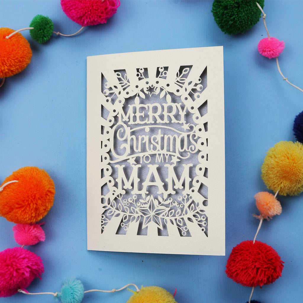 Laser cut Mam Christmas card with 'Merry Christmas to my Mam' text on a blue background with colourful pom-poms.