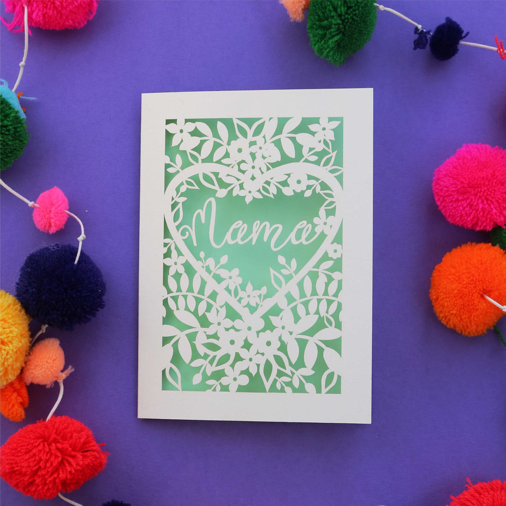 A cut out mother's day card with "mama" inside a heart surrounded by flowers