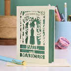 Laser-cut gay anniversary card with 'Paul and Marcus' on a table with stationery items.