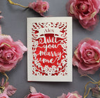 A laser cut card that says "Name, will you marry me?"