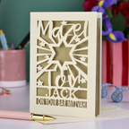 Decorative Laser cut Bar Mitzvah card with cut-out text, 'Mazel Tov Jack on your Bar mitzvah' on a table with stationery items.