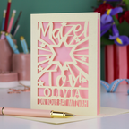 Personalized Bat Mitzvah card with decorative cut-out  star design and text 'Mazel Tov Olivia on your Bat Mitzvah' on a desk with stationery items.