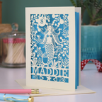 A laser cut mermaid birthday card, personalised with the age in cut out stencil font in a bubble, and the name across the bottom of the card. The design is a mermaid surrounded by bubbles, diamonds, fish and sea plants