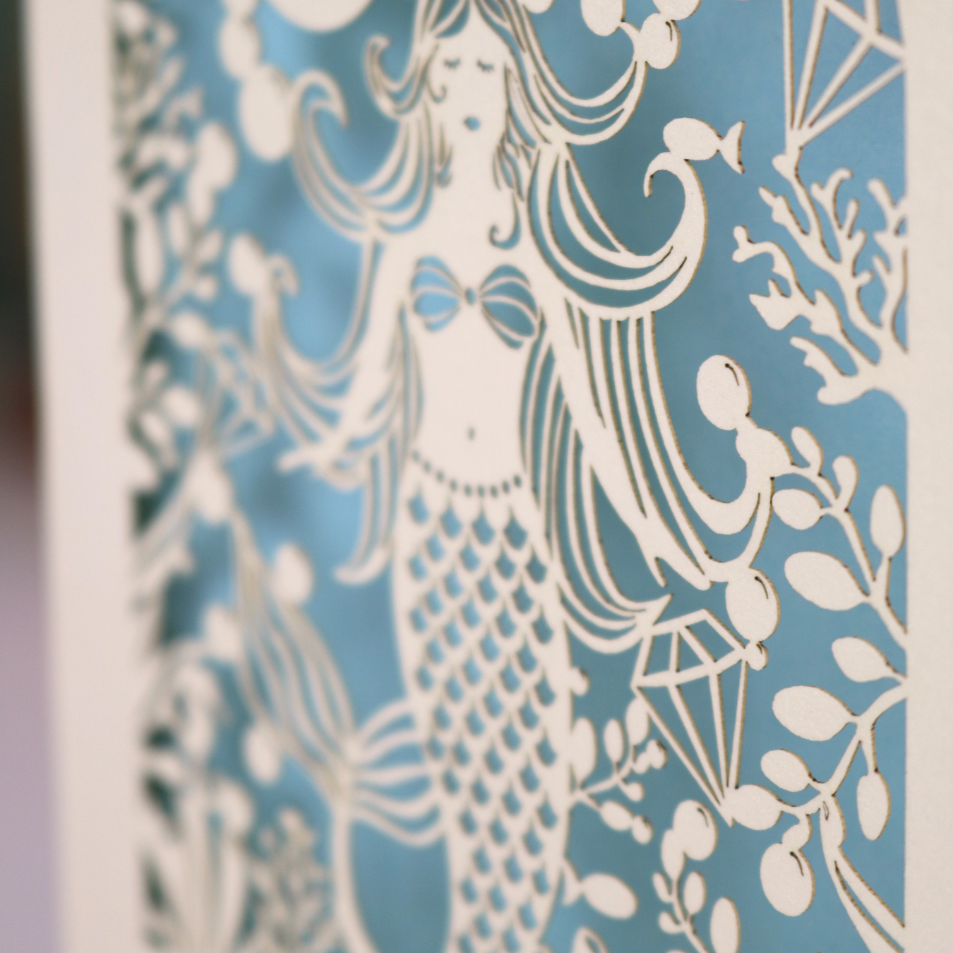 A close up detail of a laser cut mermaid birthday card