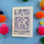 Cute Personalised birthday Card with carousel design and 'FREYA' text on a blue background with colourful pom-poms.
