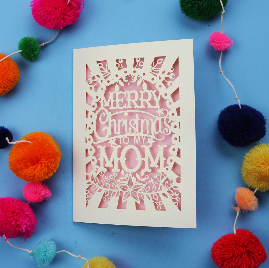 Laser cut Mom Card with 'Merry Christmas to my Mom' text surrounded by colourful pom-poms on a blue background