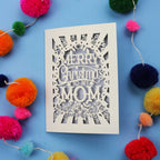 Laser cut Mom Card with 'Merry Christmas to my Mom' text surrounded by colourful pom-poms on a blue background
