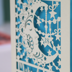 Laser cut moon 18th Birthday card with blue star and moon design on a desk with stationery items.