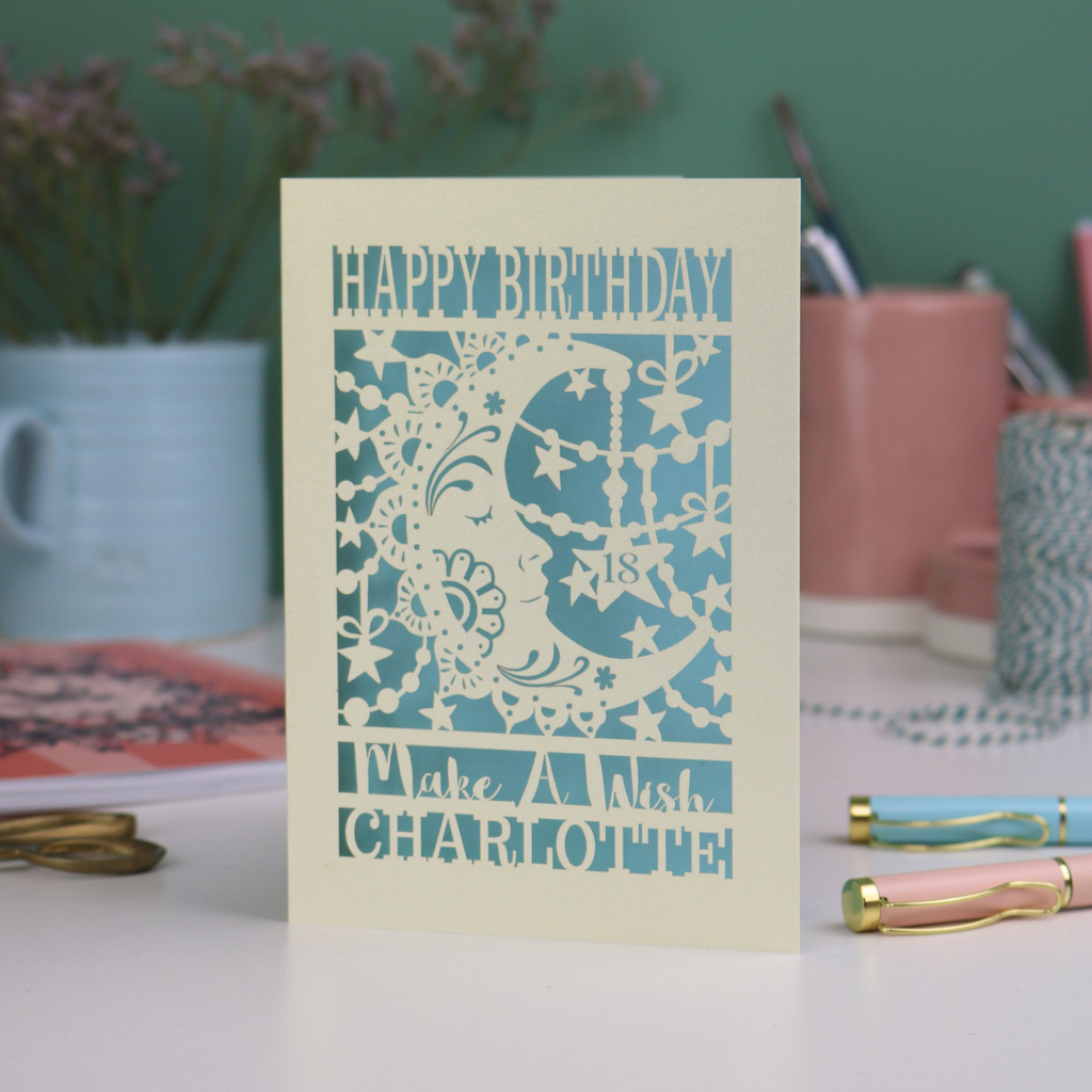 Laser cut moon 18th Birthday card with blue star and moon design on a desk with stationery items.