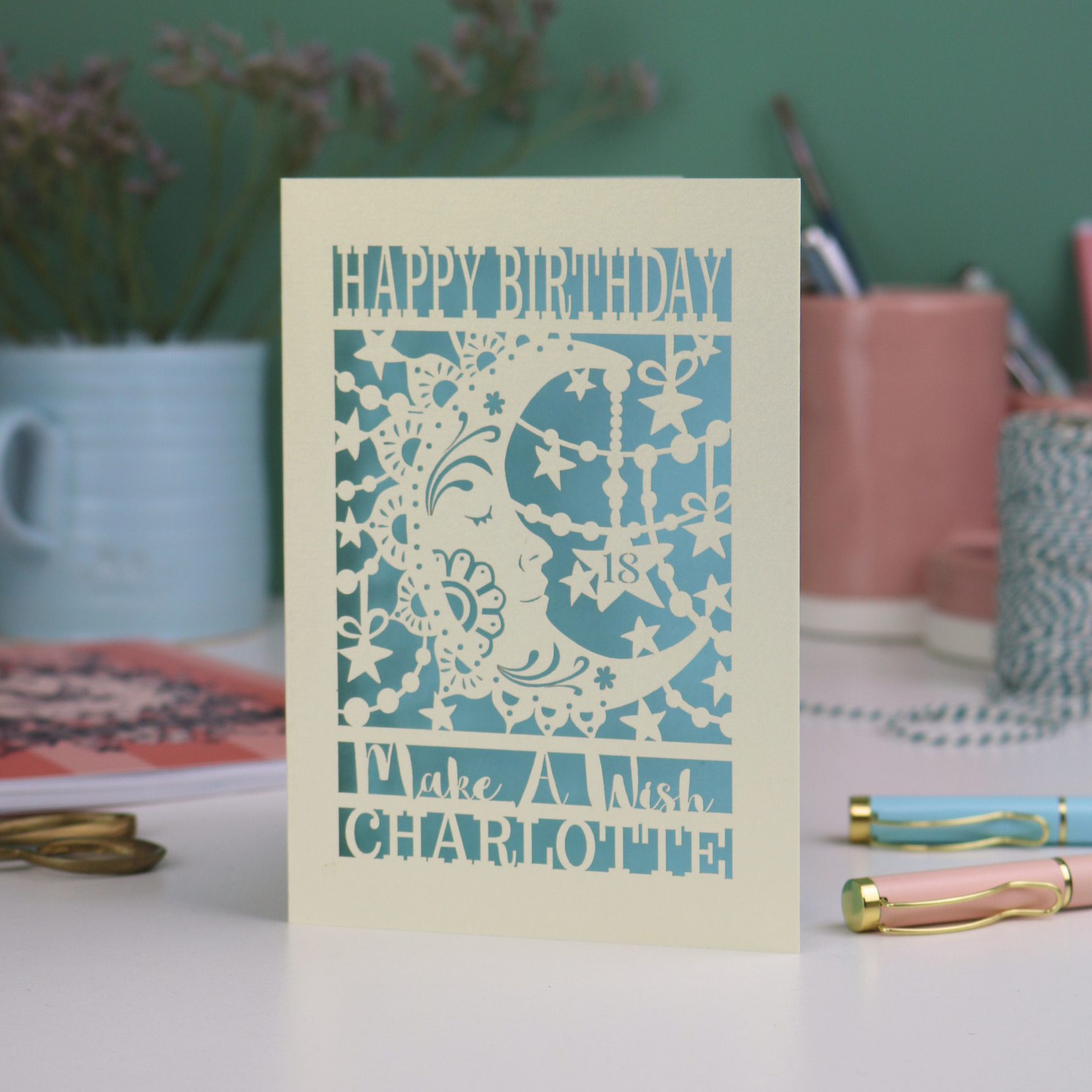 Laser cut moon 18th Birthday card with blue star and moon design on a desk with stationery items.
