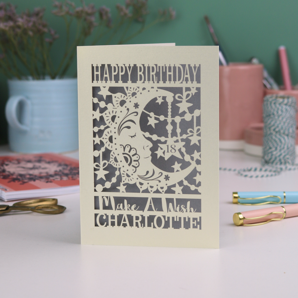 Laser cut moon 18th Birthday card with blue star and moon design on a desk with stationery items.