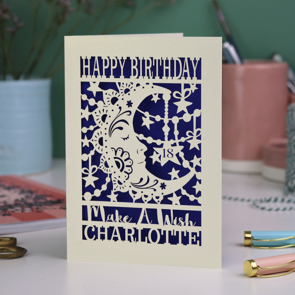 Laser cut moon 18th Birthday card with blue star and moon design on a desk with stationery items.