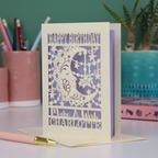 A personalised Birthday card with laser cut crescent moon design and text, 'Happy Birthday, Make a Wish Charlotte', on a desk with stationery items.
