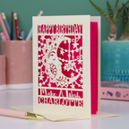 A personalised Birthday card with laser cut crescent moon design and text, 'Happy Birthday, Make a Wish Charlotte', on a desk with stationery items.