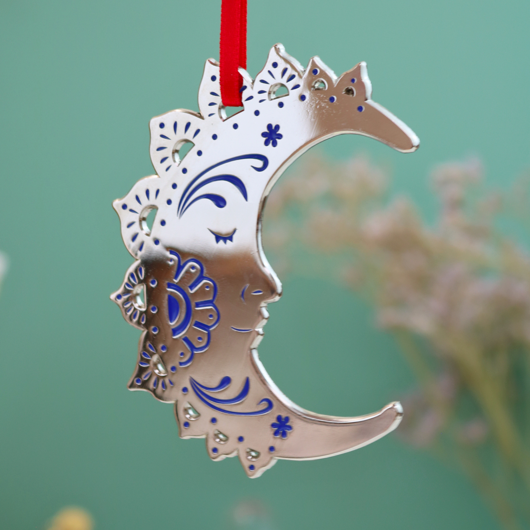 Decorative ornament shaped like a crescent moon with intricate patterns on a green background