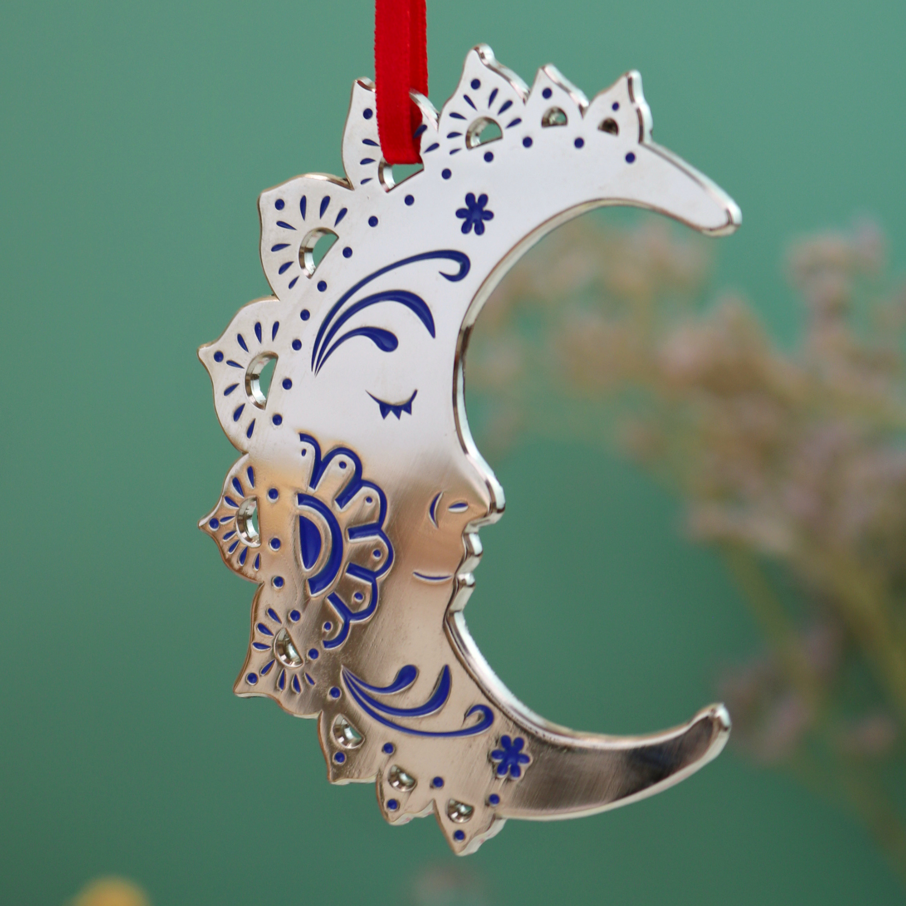 Decorative moon Christmas ornament with blue details on a green background