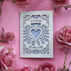 A cream cut out Mother's Day card that says "With love on Mothering Sunday". Card has a heart and flower details and a lilac paper insert