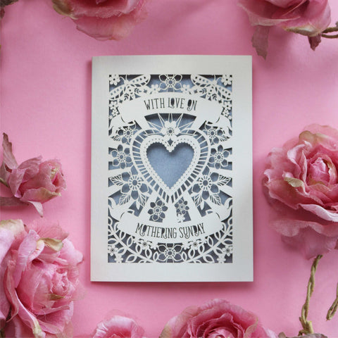 A cream laser cut Mothering Sunday card that says "With love on Mothering Sunday". Card has a heart and flower details and a silver paper insert - A6 (small) / Silver