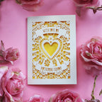 A cream laser cut Mothering Sunday card that says "With love on Mothering Sunday". Card has a heart and flower details and a yellow paper insert