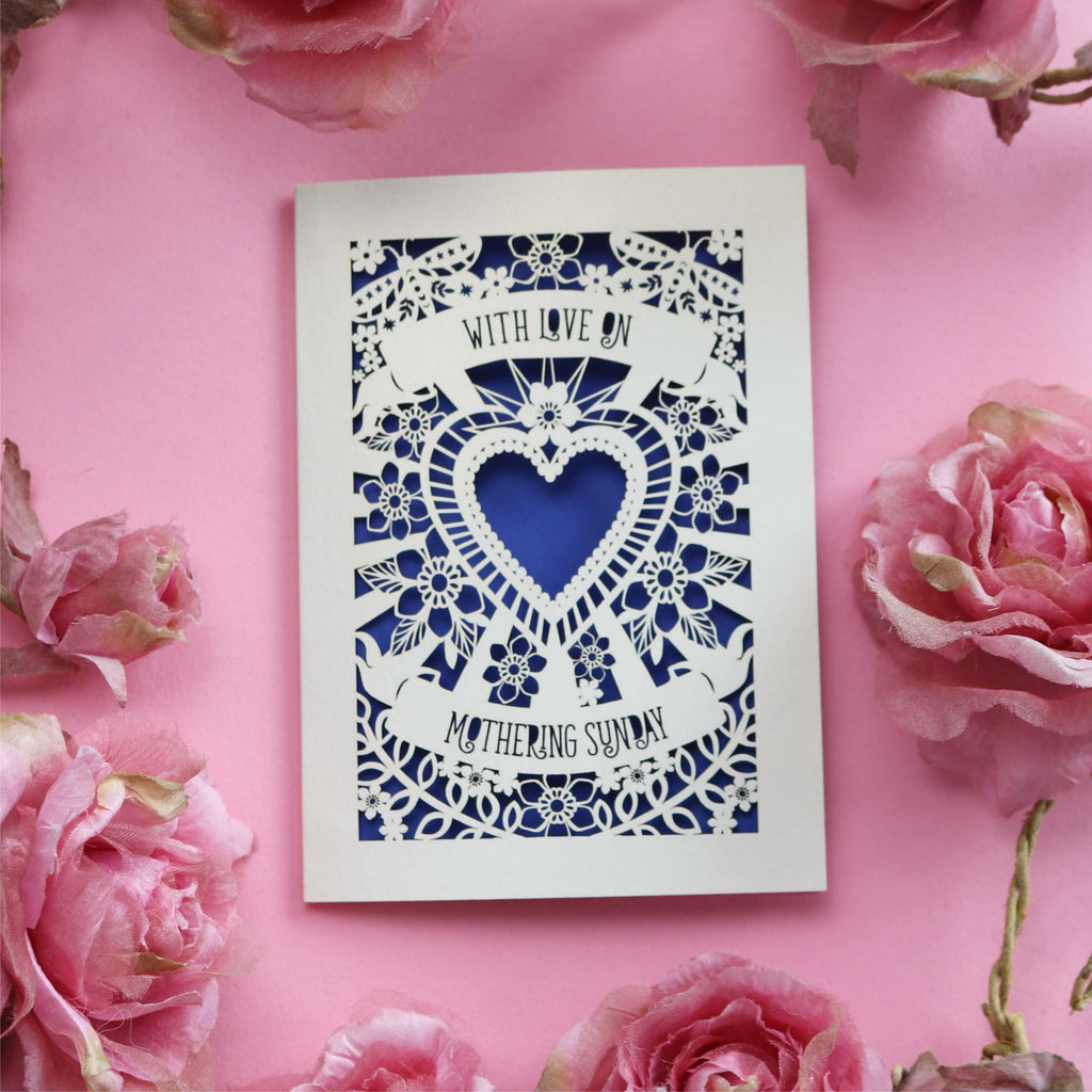 A cream laser cut Mothering Sunday card that says "With love on Mothering Sunday". Card has a heart and flower details and a violet paper insert