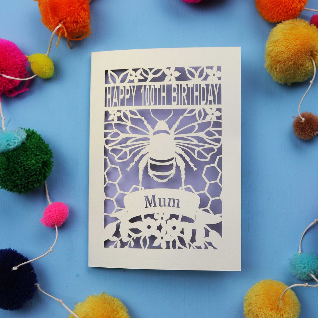 Laser-cut 100th birthday card for 'Mum' with bee design on a blue background with colourful pom-poms.