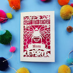 Laser-cut 100th birthday card for 'Mum' with bee design on a blue background with colourful pom-poms.