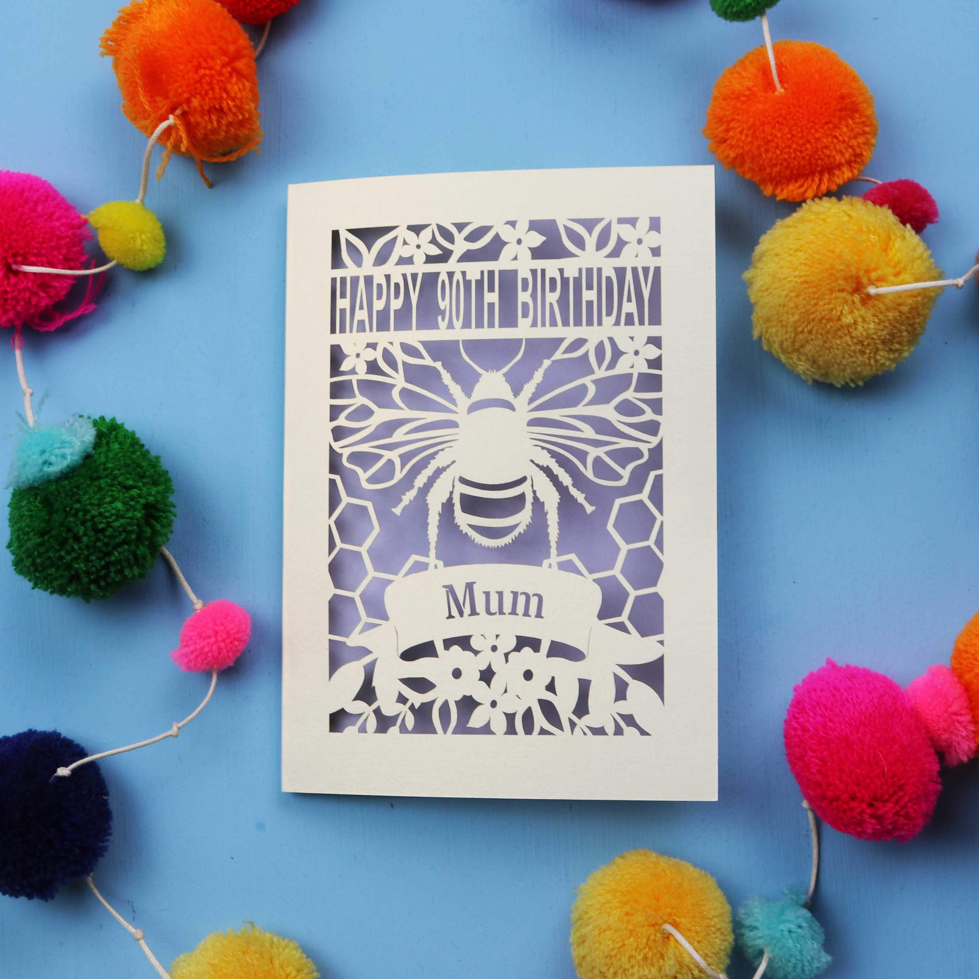 90th Birthday card with bee design and colourful pom-poms on a blue background